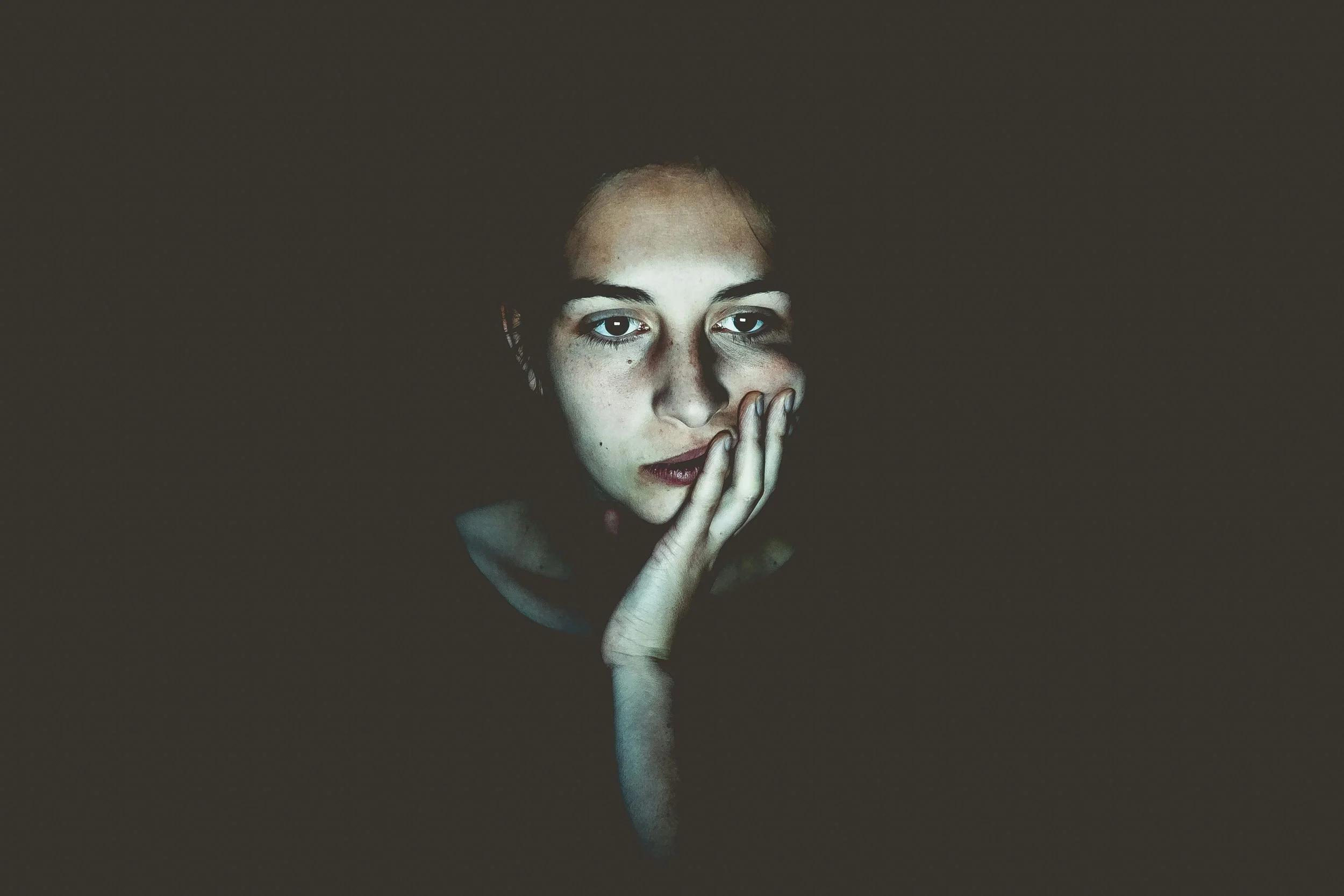 Hands holding a phone on a video call, representing the muted-but-visible dynamic of remote communication